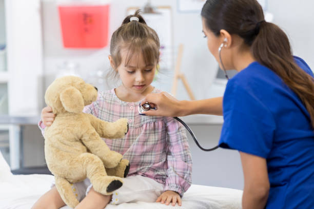 menina aguarda pacientemente enquanto médico ouve batimento cardíaco - nurse reaching women doctor - fotografias e filmes do acervo