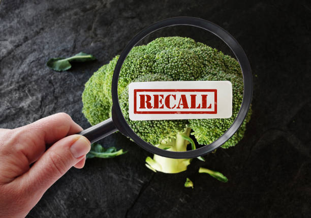 Food safety recall Hand with magnifying glass looking at broccoli Recall label food recall stock pictures, royalty-free photos & images