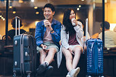 Two asian tourists with suitcases spending happy time in cafe