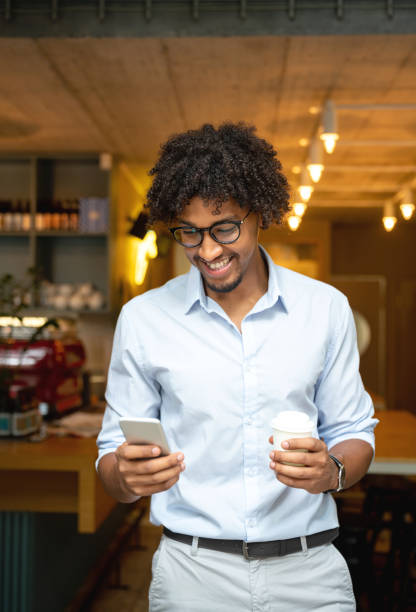 istock Man buying a cup of coffee to go at a cafe while texting 1056372974