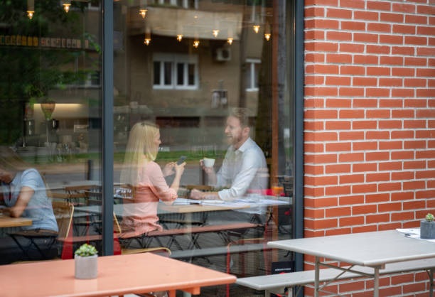 Happy couple on a date at a cafe Happy couple on a date at a cafe drinking coffee and smiling while talking - lifestyle concepts restaurant window stock pictures, royalty-free photos & images