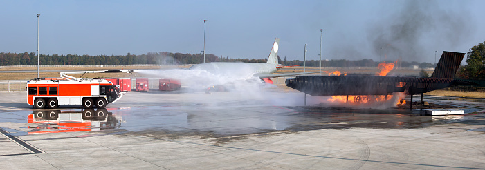 Airport crash tender and jet dummy on fire during a fire drill at the airport. All identifiable numbers and logos have been removed carefully