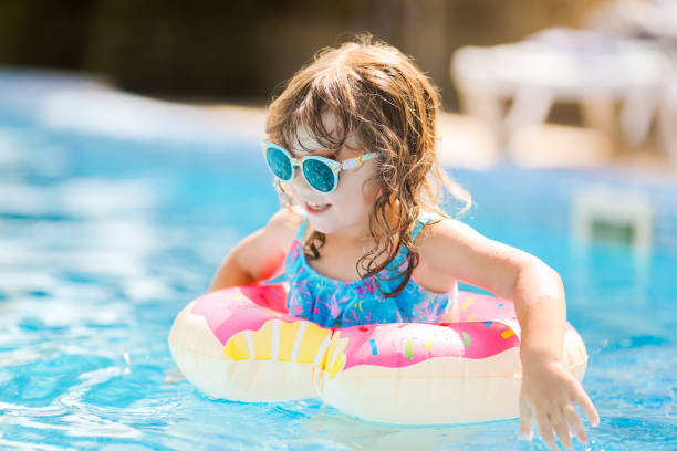 istock Child in swimming pool on funny inflatable donut float ring, learning how to swim. 1056388522