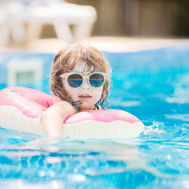 istock Child in swimming pool on funny inflatable donut float ring, learning how to swim. 1056388590