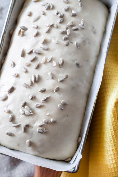 istock Raw yeast dough in tin form, ready for baking bread with sunflower seeds 1056392308