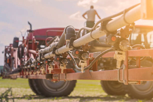 selbstfahrende feldspritze arbeitet auf einer wiese unter blauem himmel mit wolken - spraying agriculture farm herbicide stock-fotos und bilder