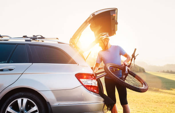 uomo che toglie la bicicletta dal bagagliaio di un'auto - bicycle cycling men riding foto e immagini stock