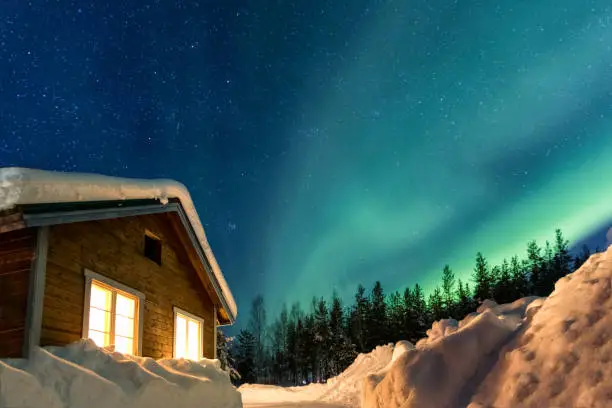 Winter landscape with wooden house under a beautiful starry sky and Northern Lights, Sweden