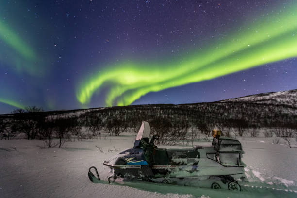 красивое зеленое северное сияние и снегоход на переднем плане, норвегия - snowmobiling adventure snow travel стоковые фото и изображения