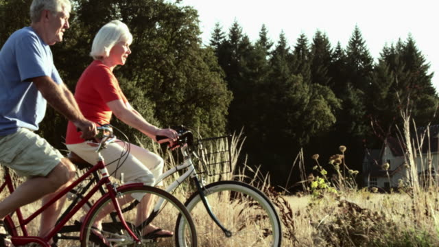 HD 1080p - シニアカップルは、一緒に自転車に乗って時間を楽しむ。 ワイドショット。