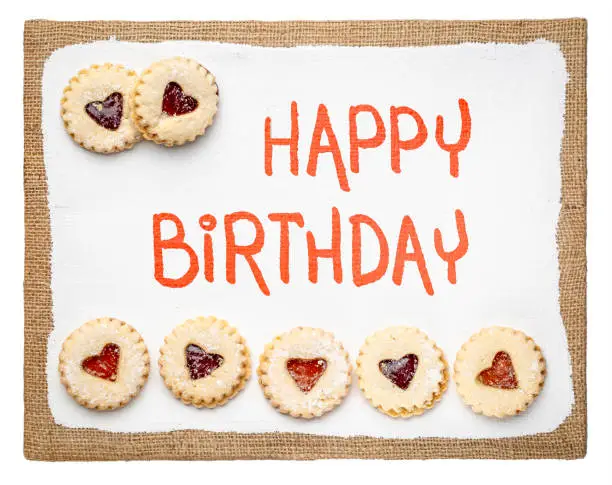 Happy Birthday - handwriting on a primed art canvas  with jam heart biscuits