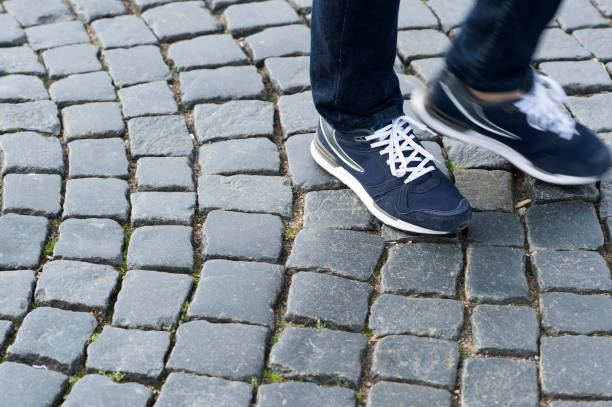 istock Legs in modern blue sneakers on the antique pavement. Start a new step 1056419436