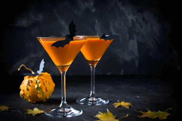 Photo of Halloween pumpkin orange cocktails. Festive drink. Halloween party. Funny Pumpkin with holiday decorations