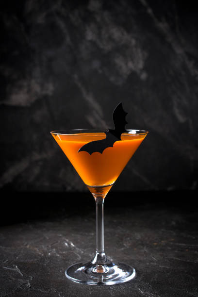 istock Orange pumpkin  martini Halloween drink for party over black background with copy space 1056420214
