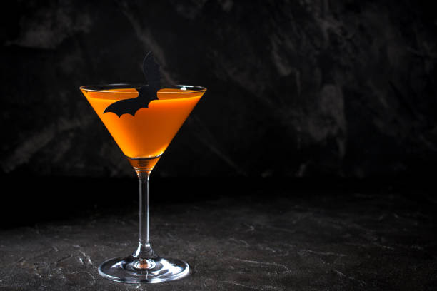 istock Orange pumpkin  martini Halloween drink for party over black background with copy space 1056420278