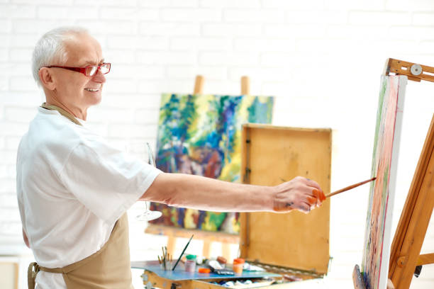 istock Talented male painter drawing picture in art studio using paint and brush. 1056430722