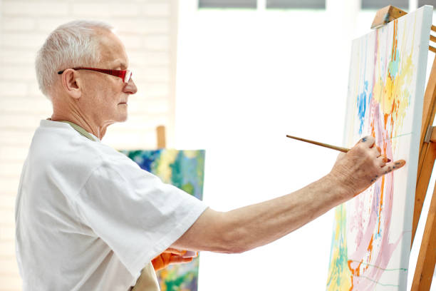 istock Creative senior painter drawing colorful picture at bright studio. 1056430738