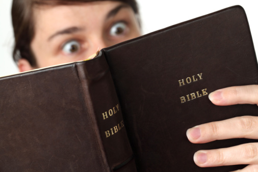 Young woman reading the Bible with surprised look