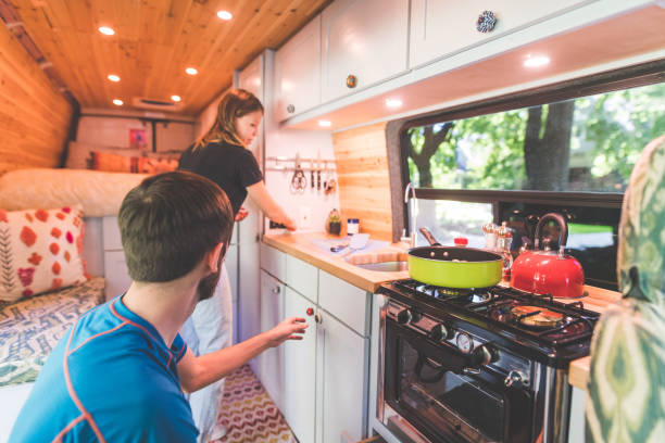 Millennial couple cook breakfast in the van they live in A young couple live in a van. They're making breakfast and she is standing by the sink while he reaches to pick something up off the counter. tiny house photos stock pictures, royalty-free photos & images