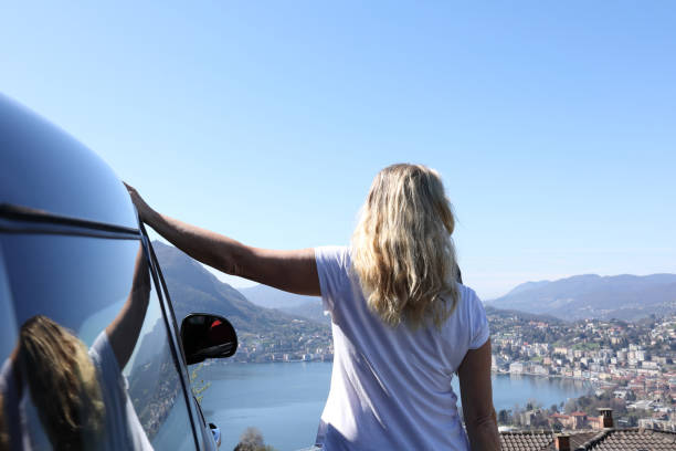 istock Woman leans against car while looking out at view 1056441234