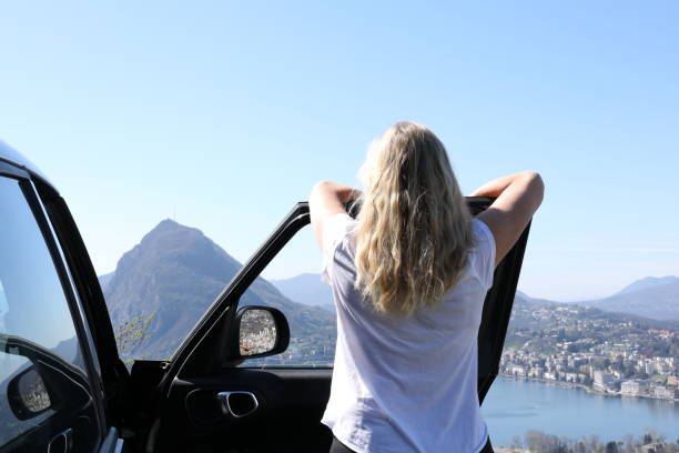 istock Woman leans against car while looking out at view 1056441364