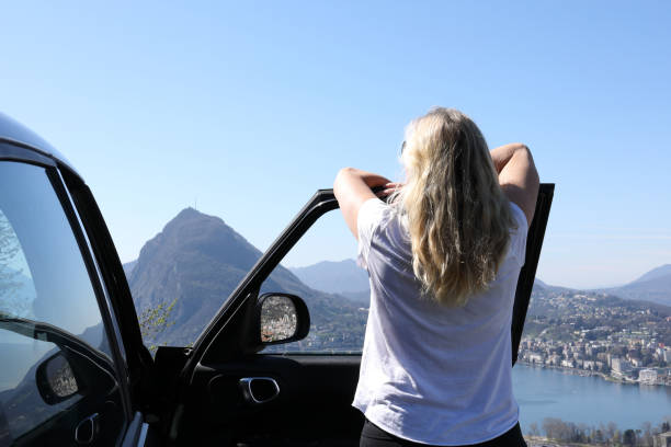 istock Woman leans against car while looking out at view 1056441370