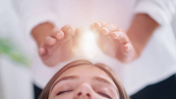 nahaufnahme einer entspannten jungen frau mit reiki heilung behandlung - hands in head stock-fotos und bilder