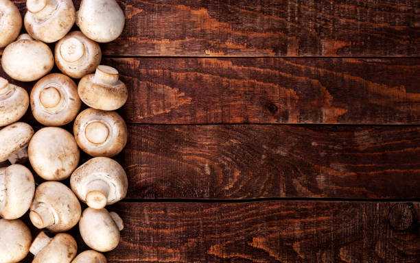 istock Fresh champignon mushrooms on wooden table, top view. Copy space 1056443282