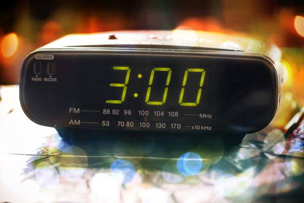 istock Black digital alarm radio clock.Alarm radio clock indicating time to wake up.Digital clock closeup displaying 3:00 o'clock. 1056445810