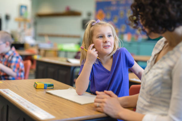 istock First grade girl talking with her teacher in the classroom 1056453134