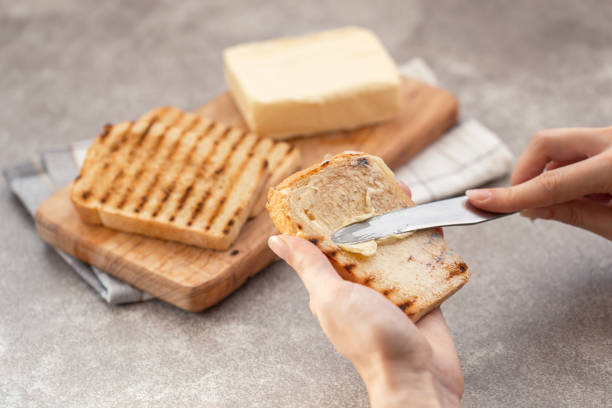 istock Female hand butters toasts for breakfast on the grey slate background 1056463064