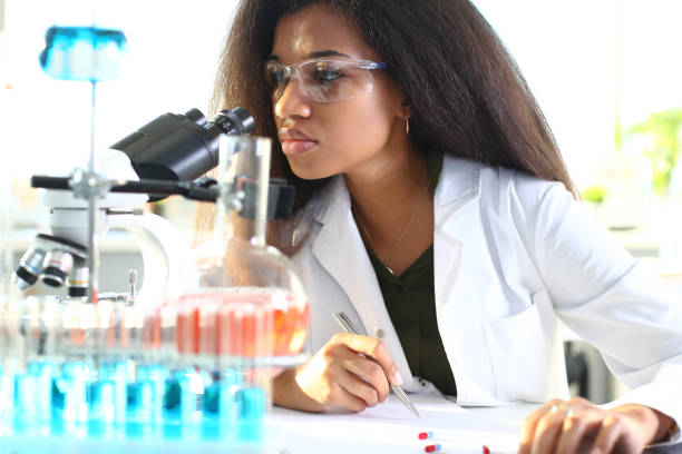 Black woman scientist student chemist in protective Black woman scientist student chemist in protective goggles are conducting research using microscope for bacterial contamination of water to search for vaccine to treat diseases in medicine. african american scientist stock pictures, royalty-free photos & images
