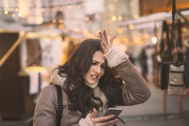 giovane donna caucasica che usa lo smartphone e tiene la testa mentre si trova per strada. - mad expression image front view horizontal foto e immagini stock