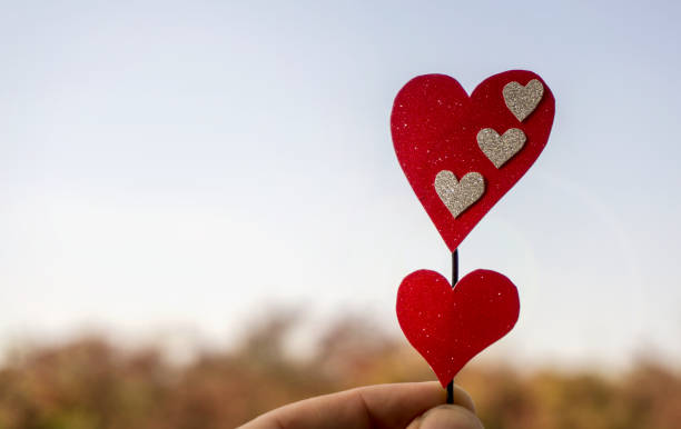istock Hand holding hearts high up in the sky, closeup 1056469534
