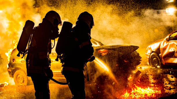 istock Rear view of two firefighters extinguishing a burning vehicle 1056471558