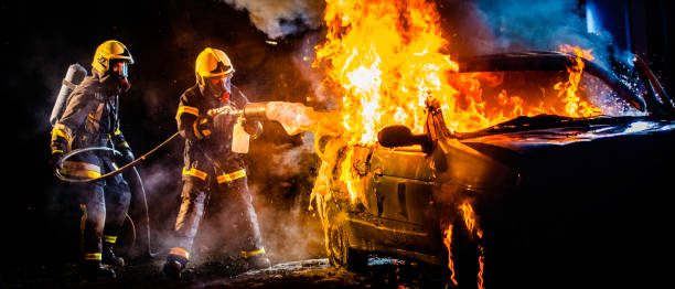 istock Two firefighters extinguishing a burning car with foam 1056471590
