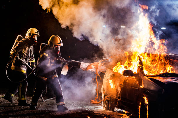 istock Two firefighters extinguishing a burning car with foam 1056471594
