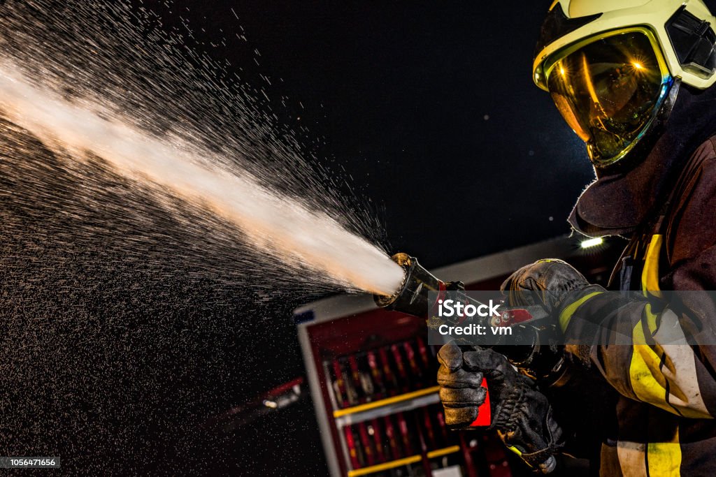 Nahaufnahme eines Feuerwehrmannes Spritzen Feuerwehrschlauch in Betrieb - Lizenzfrei Feuerwehrschlauch Stock-Foto