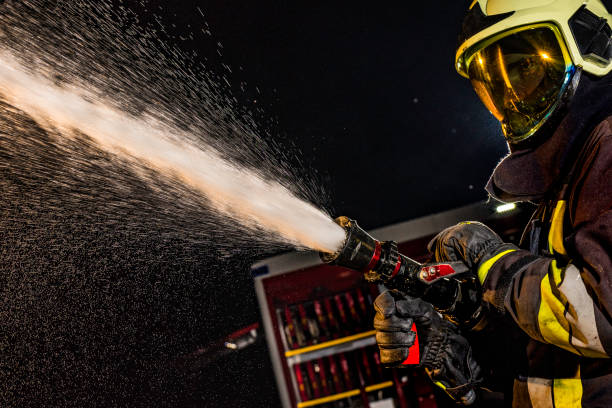 istock Close-up of a firefighter operating a spraying fire hose 1056471656