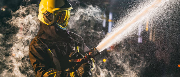 istock Fireman spraying water from hose surrounded by smoke 1056471668