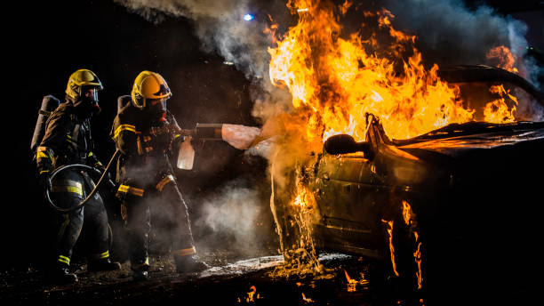 istock Two firefighters extinguishing a burning vehicle at night 1056471678