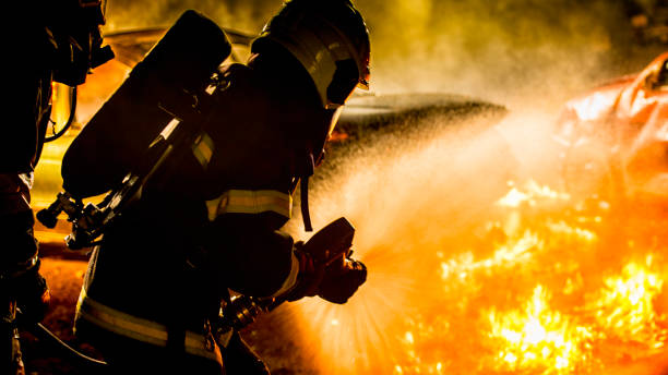 istock Rear view of two firefighters extinguishing a burning vehicle 1056471692