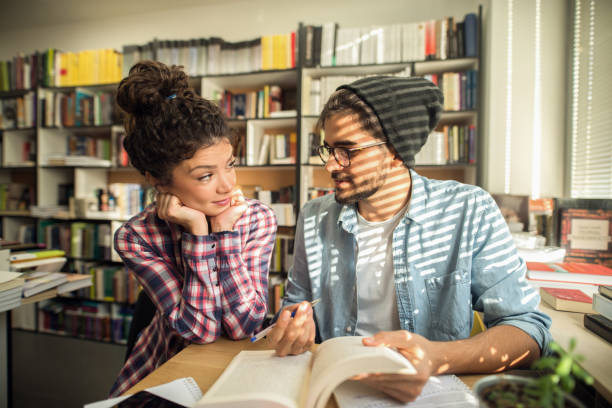 istock Classmates learning togeter for exams in library. Male student explaining to his friend how to solve problem. 1056477434