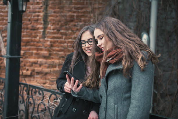istock Two female friends using phone downtown 1056481198