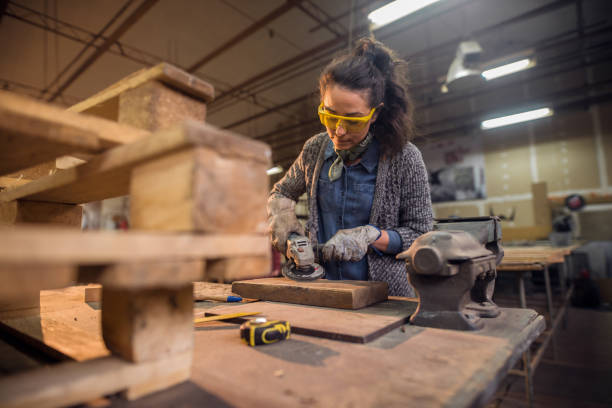 istock Female carpenter working with sander while standing surrounded with wood. 1056482598