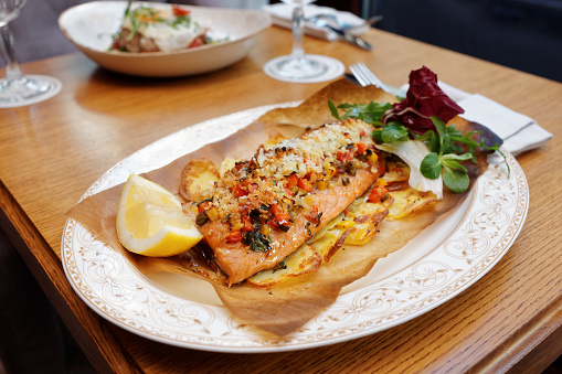 Grilled trout with vegetables, bread crumbs and potatoes on restaurant table, Italian cuisine