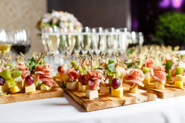 the buffet at the reception. Glasses of wine and champagne. Assortment of canapes on wooden board. Banquet service. catering food, snacks with cheese, jamon, prosciutto and fruit the buffet at the reception. Assortment of canapes. Banquet service. catering food, snacks with cheese, jamon, prosciutto and fruit restaurant food canapes appetizers stock pictures, royalty-free photos & images