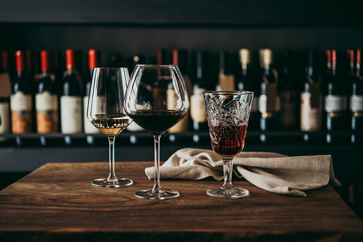 Different glasses of wine served on a wooden table in a bar or a wine shop.