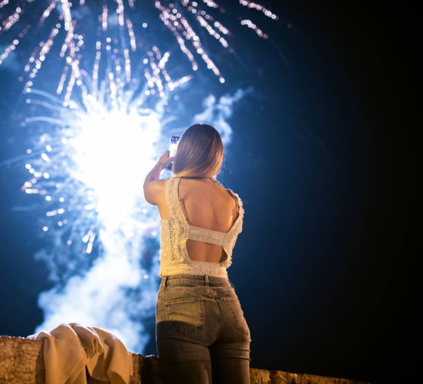 istock Young woman taking photos of fireworks 1056498232