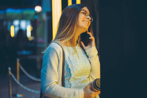 istock Young woman using phone downtown at night 1056499894